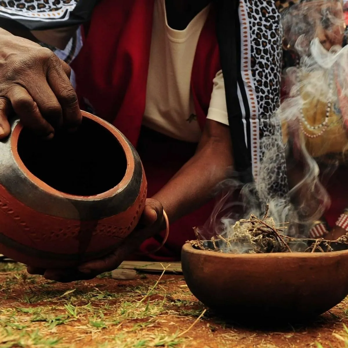 Traditional African spiritual practitioner performing botanical herbal purification cleansing bath on person in sacred water